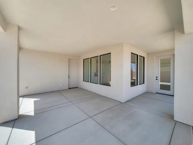 Covered patio with a concrete surface, featuring multiple exterior doors and black-framed windows