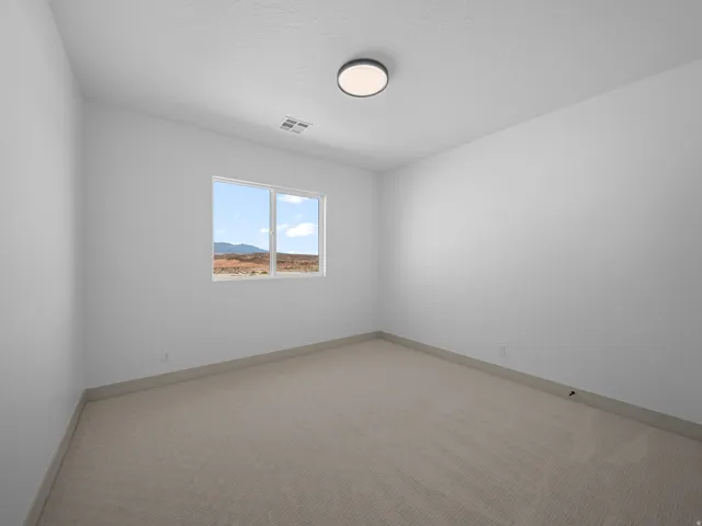 Neutral carpeting, white wall finishes, and a single window offering a distant mountain backdrop
