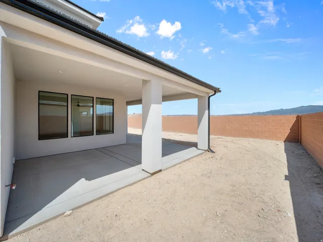 Expansive covered patio with concrete flooring, supported by stucco columns