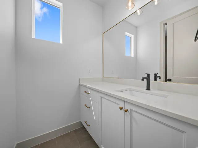 White vanity with gold-finish hardware, integrated sink, and matte black faucet