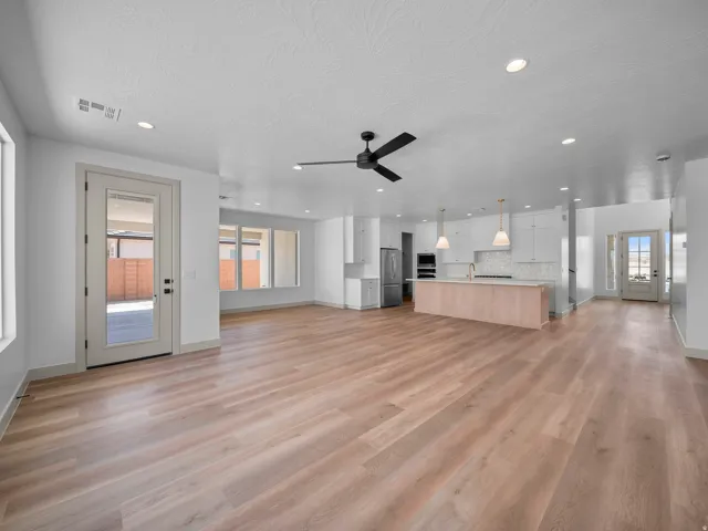Open-concept living space featuring wood-finish flooring, recessed lighting, and a modern kitchen with white cabinetry