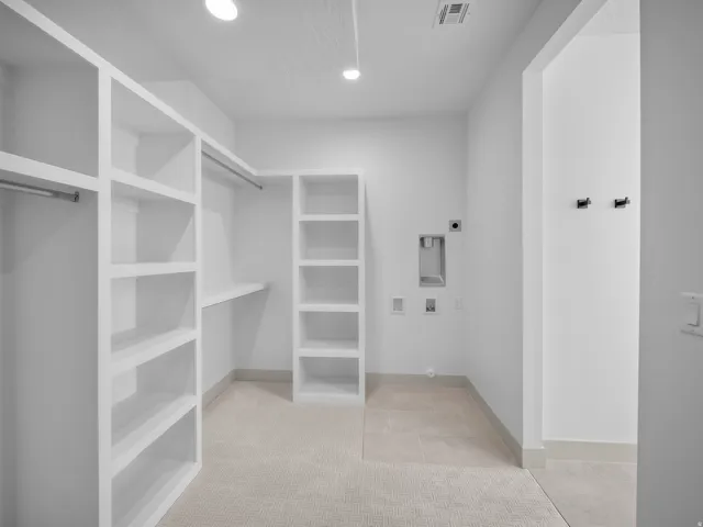 Built-in shelving, hanging rods, recessed lighting, and a tile flooring area with utility hookups