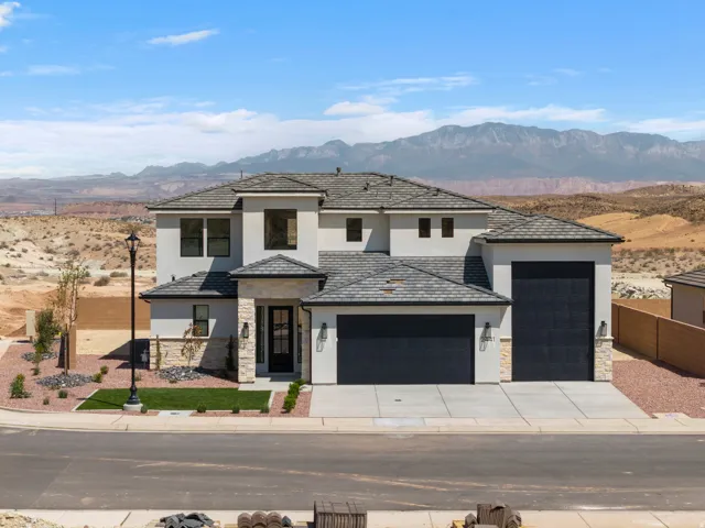 Contemporary stucco exterior with stone accents, a multi-car garage, and a tiled roof