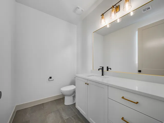 Spacious vanity with white cabinetry, gold-finish hardware, and a matte black faucet