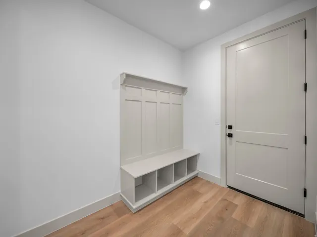 Built-in storage bench with cubbies, light wood-finish flooring, and a recessed ceiling light