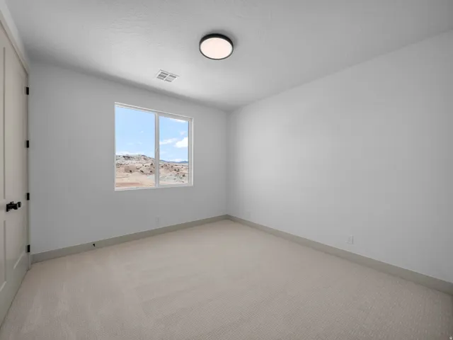 Carpeted room featuring a white door with black hardware, a large window, and a flush-mount ceiling light
