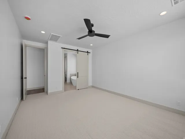 Carpeted flooring, recessed lighting, matte black ceiling fan, and barn door entry to bathroom with modern toilet