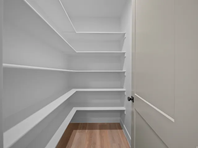 White built-in shelving, wood-finish flooring, and a paneled door with matte black hardware