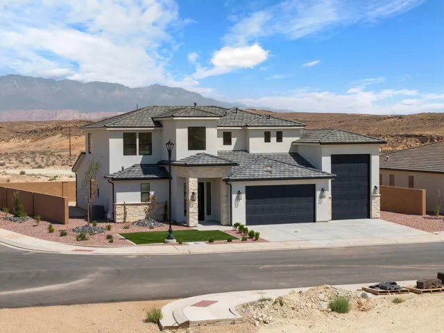 Contemporary stucco exterior with stone accents, a multi-car garage, concrete driveway, and a tiled roof