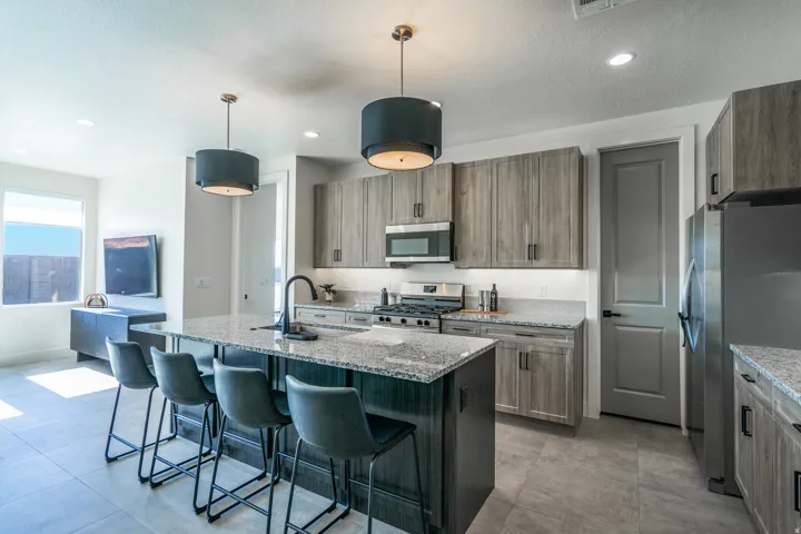 Kitchen with an extended island, overhead pendant lighting, stainless steel appliances, and wood-finish cabinetry