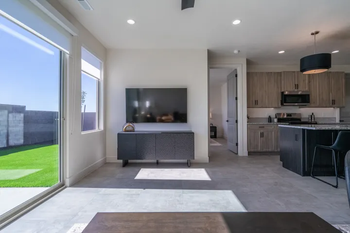 Open-concept living space featuring a wall-mounted flat-screen television, built-in media console, and direct access to a manicured lawn through sliding glass doors