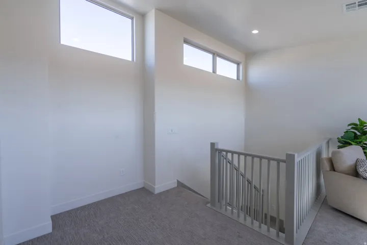 Bright upper-level room with abundant natural light from dual transom windows and recessed ceiling lighting