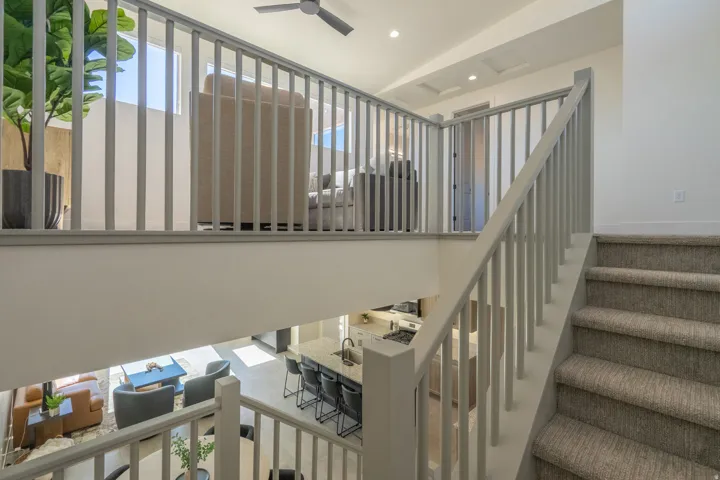 Open-concept mezzanine level featuring steel railings, recessed ceiling lighting, and a curved staircase with neutral-toned treads