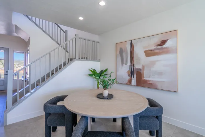 Recessed lighting illuminates the modern staircase with gray balusters, complemented by light-toned wall finishes and tile flooring