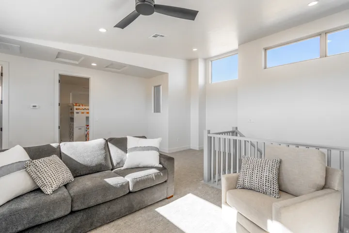 Bright, open living space featuring a gray upholstered sofa, neutral wood-finish flooring, and abundant natural light from expansive windows