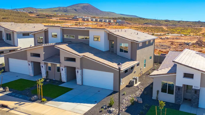 Modern townhomes featuring desert landscaping, attached garages, and a distinctive roofline