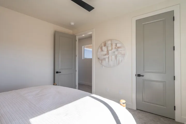 Bright secondary bedroom with neutral wall finishes, recessed ceiling lighting, and dual panel doors with matte hardware