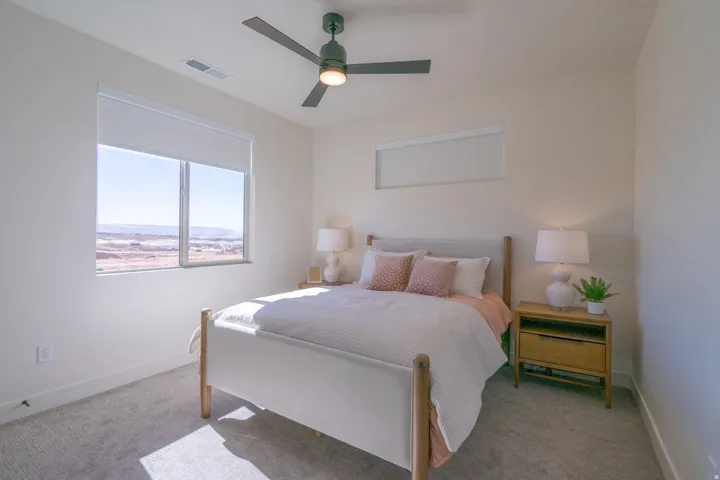 Bright bedroom with expansive windows framing scenic vistas, neutral wall finishes, and carpet flooring