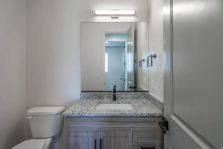 Vanity with a granite countertop, undermount sink, and dark-finish faucet