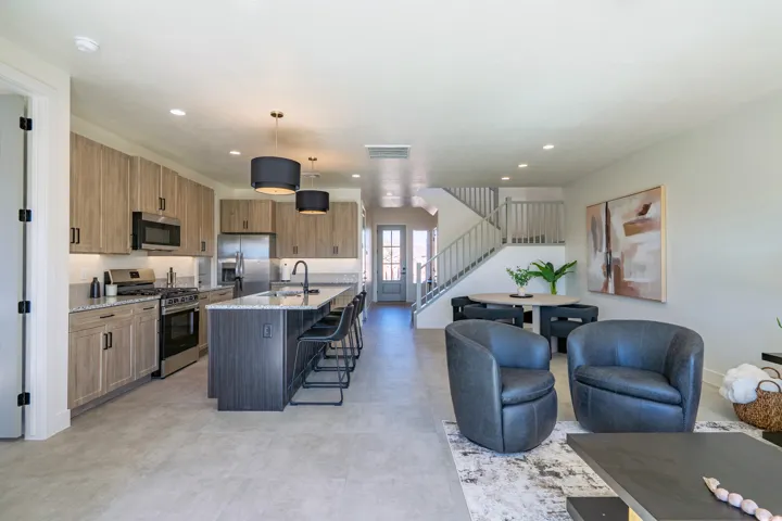 Open-concept living featuring a chef's kitchen with stainless steel appliances, wood-finish cabinetry, and a large island with seating, paired with a comfortable lounge area