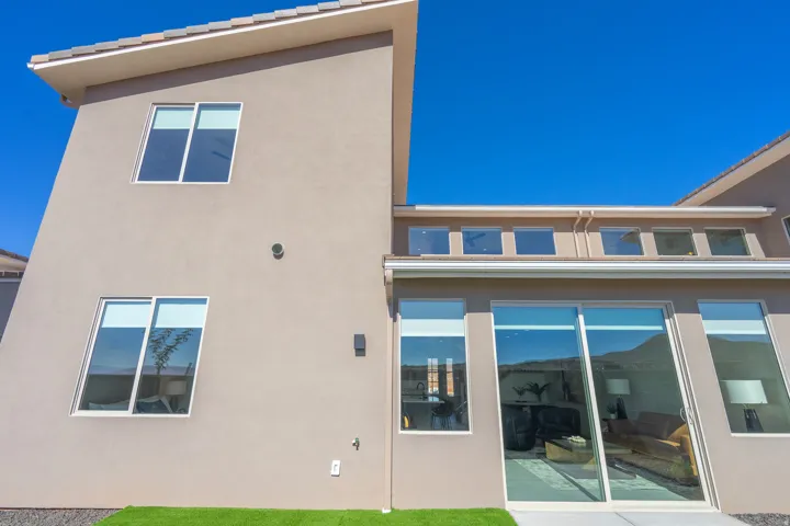 Modern architectural design featuring a two-story stucco exterior with clean geometric lines, expansive multi-panel glass sliding doors, and large dual-pane windows maximizing natural light