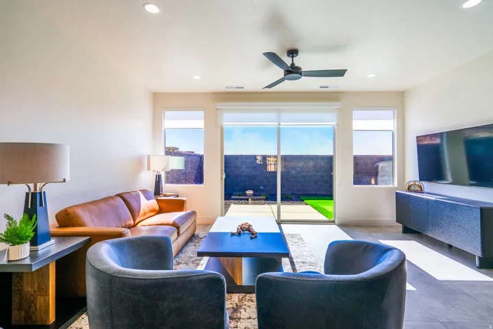 Recessed ceiling lighting, modern ceiling fan, large sliding glass door, multiple windows, and tile flooring