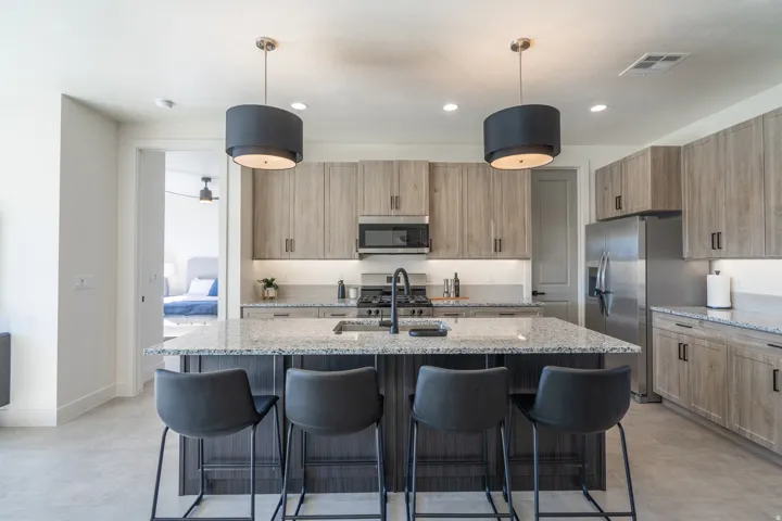Kitchen featuring a central island with granite countertop, stainless steel appliances, wood-finish cabinetry, and recessed lighting