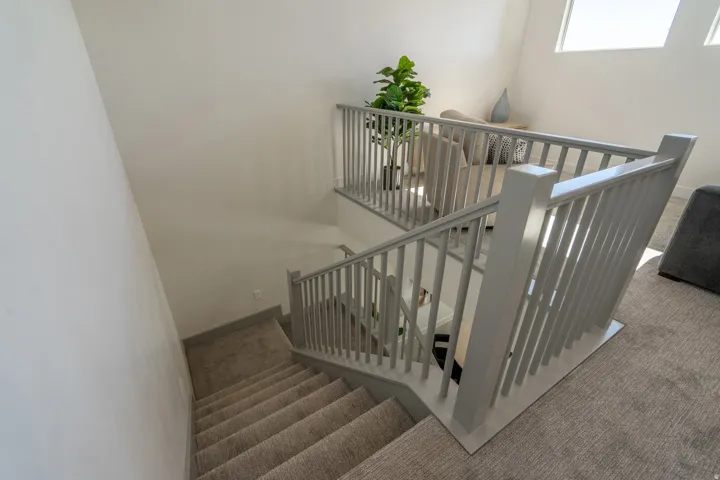 Loft-style landing featuring white vertical-slat safety railings, wood-finish stair treads, and abundant natural light from overhead skylights