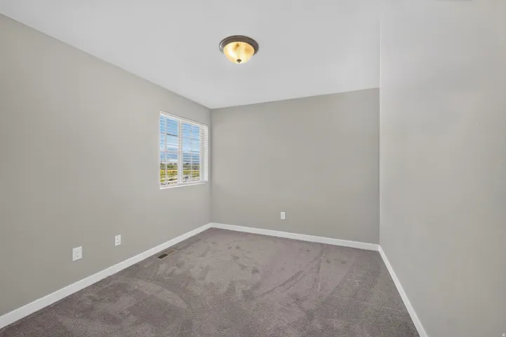 Neutral wall paint tones, gray carpeting, single window with blinds, and flush mount ceiling light fixture