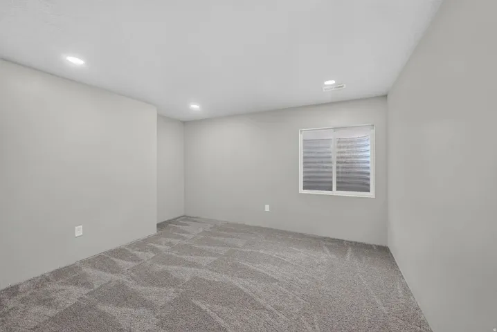 Recessed lighting, light gray wall finish, patterned carpeting, white window frame, and window blinds