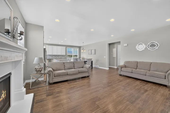 Wood-finish flooring, recessed lighting, and a white fireplace mantel