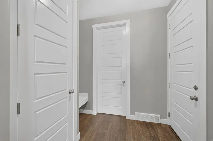 White paneled doors, neutral wall paint, wood-finish flooring, and a built-in bench