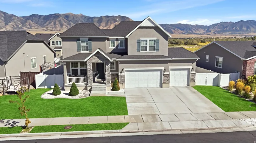 Two-story residence featuring a stone and stucco exterior, a covered front porch, an attached two-car garage, and a concrete driveway