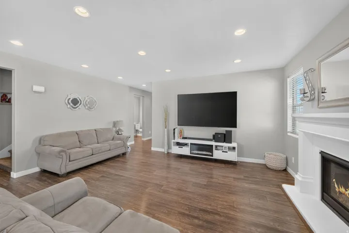 Spacious living area featuring wood-finish flooring, recessed lighting, and a white mantel fireplace
