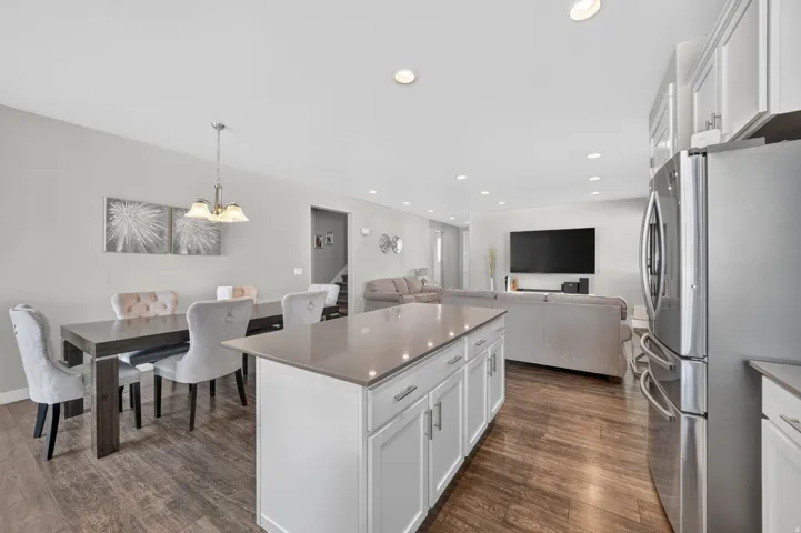 Open concept living area featuring wood-finish flooring, recessed lighting, and a kitchen island with a light-toned countertop