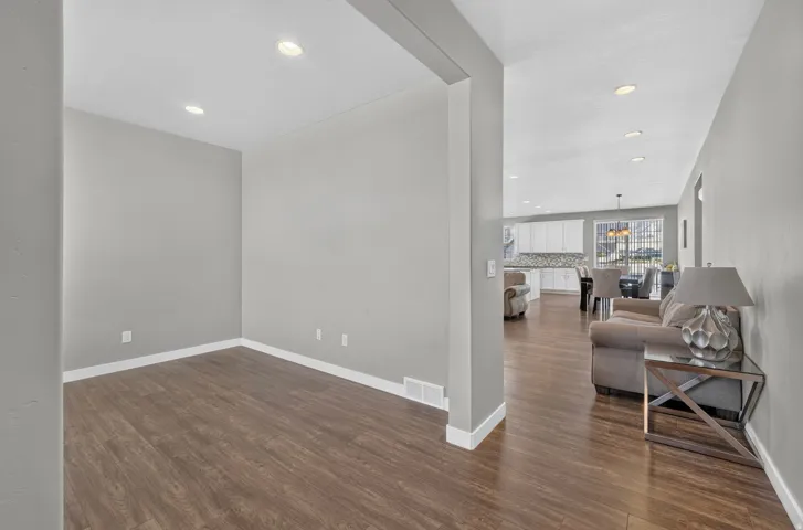 Recessed lighting, wood-finish flooring, light gray wall paint, and white trim