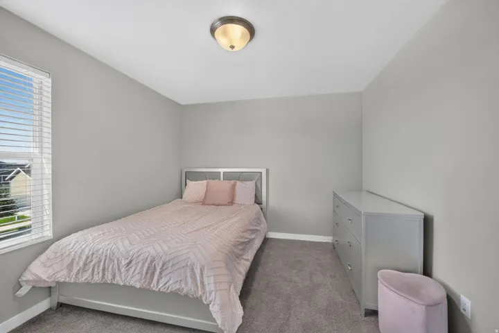 Neutral wall paint, ceiling-mounted light fixture, window with horizontal blinds, and carpeted flooring
