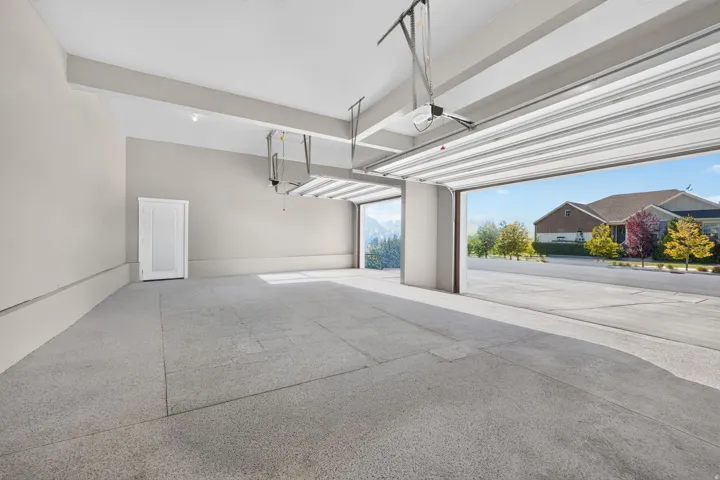 Spacious garage with light gray walls, a durable epoxy-coated floor, and dual overhead garage doors