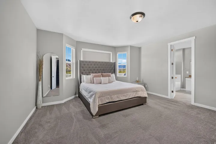 Spacious room featuring neutral carpeting, light gray wall paint, and multiple windows