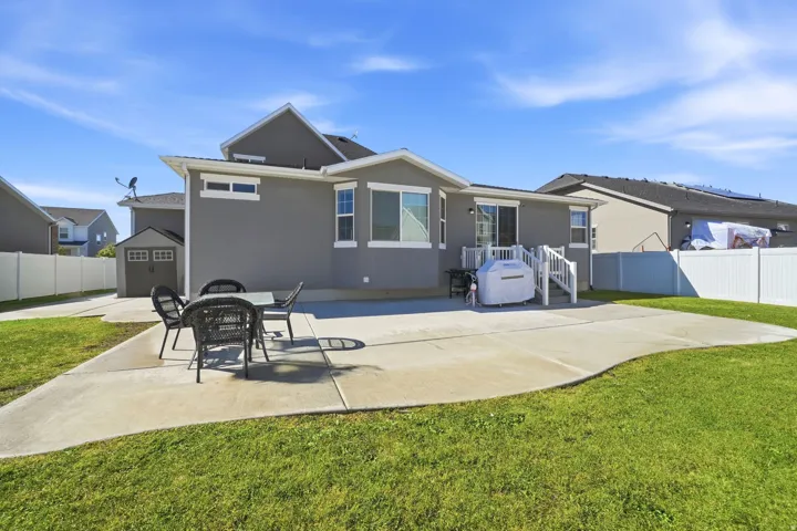 Expansive concrete patio with a white perimeter fence, a built-in storage shed, and a privacy fence