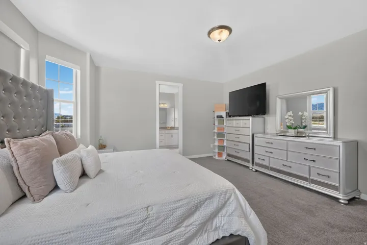 Recessed lighting, large window with natural light, gray wall color, gray carpeting, and a visible doorway to an adjoining space