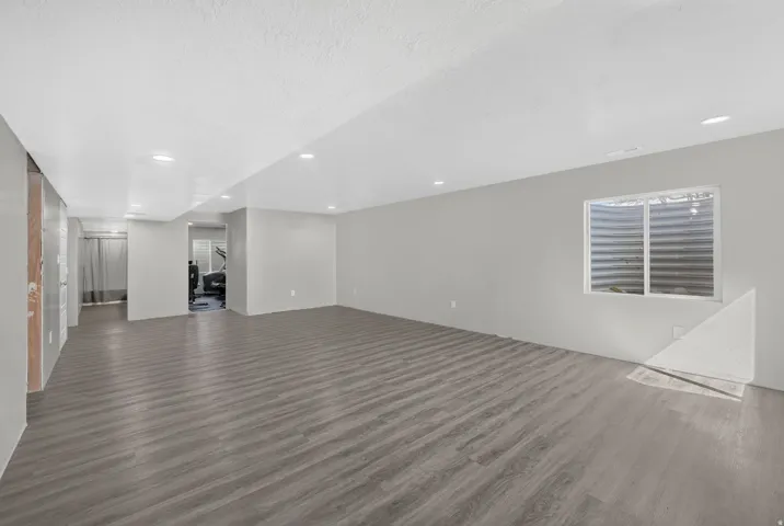 Spacious room featuring wood-finish flooring, recessed lighting, and a window with a window well