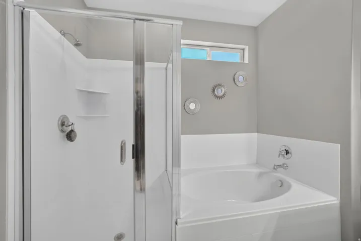 Walk-in shower with a glass enclosure, corner soaking tub, and chrome fixtures
