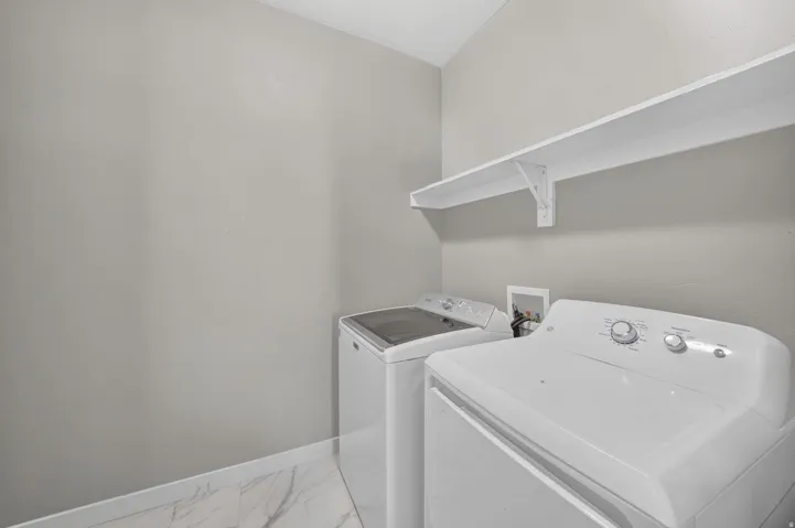 Utility space with white shelving and tile flooring