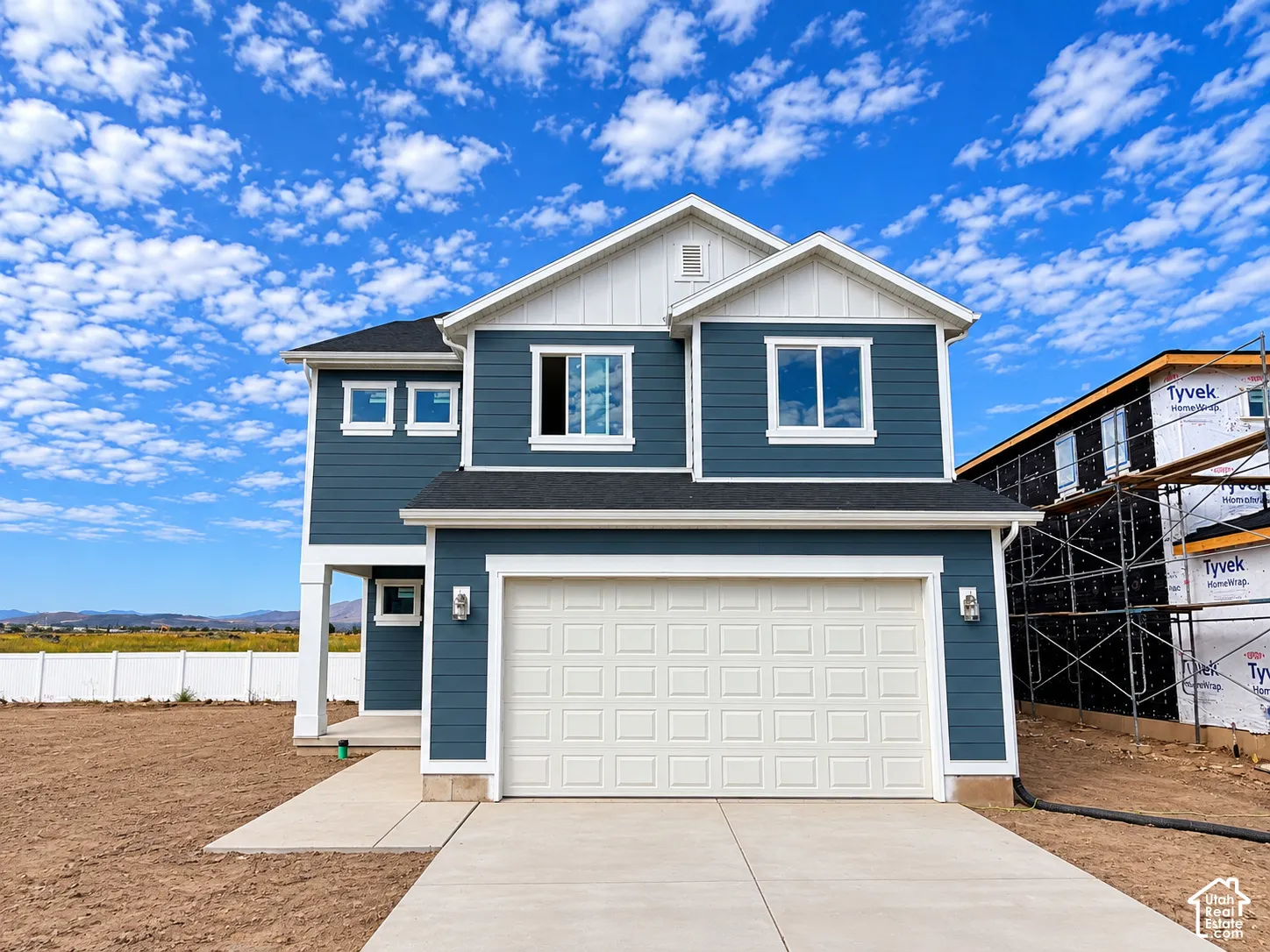 Two-story residence featuring blue siding, white trim, a gabled roofline, an attached two-car garage, and a concrete driveway