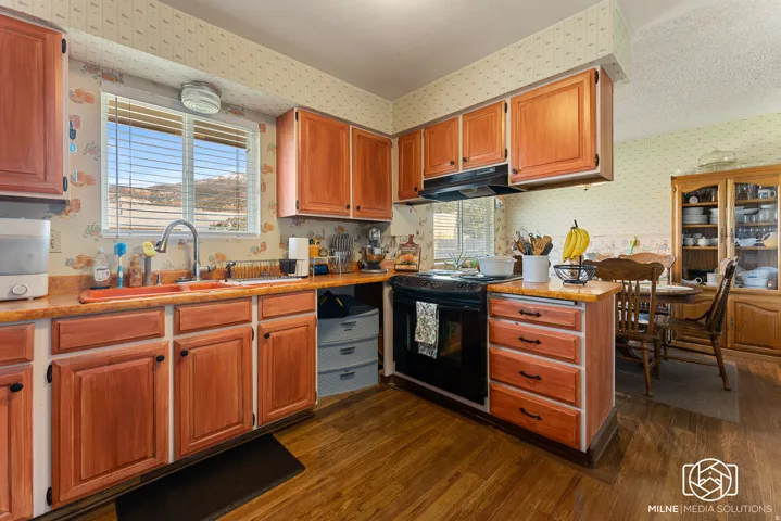 Kitchen featuring wood-finish cabinetry, built-in oven, integrated range hood, and wood-finish flooring