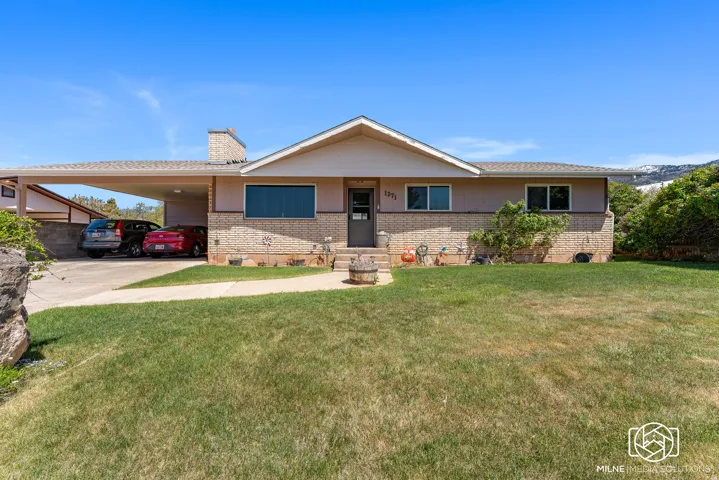 Ranch-style residence featuring a brick facade, covered carport, and a prominent front lawn