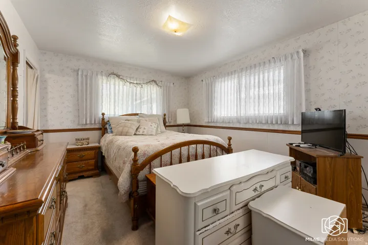 Wallpapered walls with a decorative border, wall-to-wall carpeting, and a ceiling-mounted light fixture