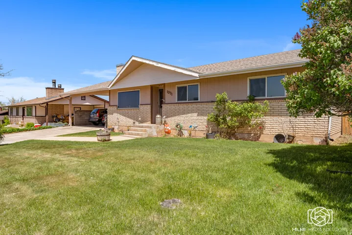 Light brick and siding exterior with a covered carport and a paved driveway