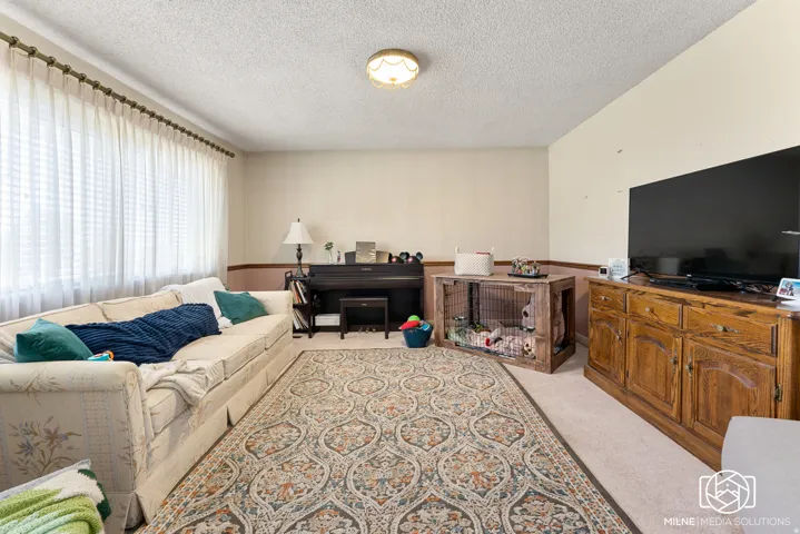 Wall-to-wall carpeting with an overhead light fixture and a full-wall window with curtains
